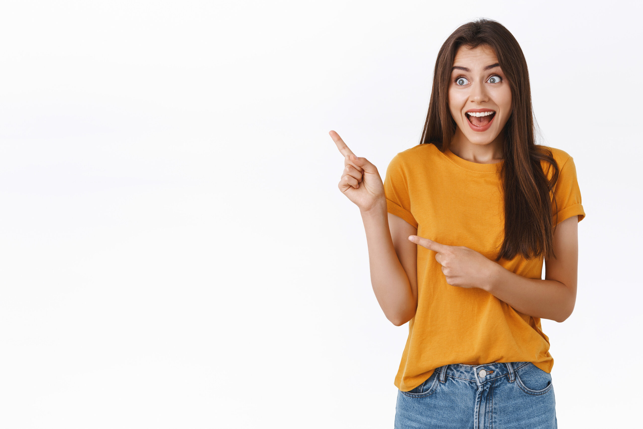 Surprised, astonished brunette girl see famous celebrity, pointing and staring thrilled upper left corner, smiling with impressed astonished expression, standing fascinated white background.
